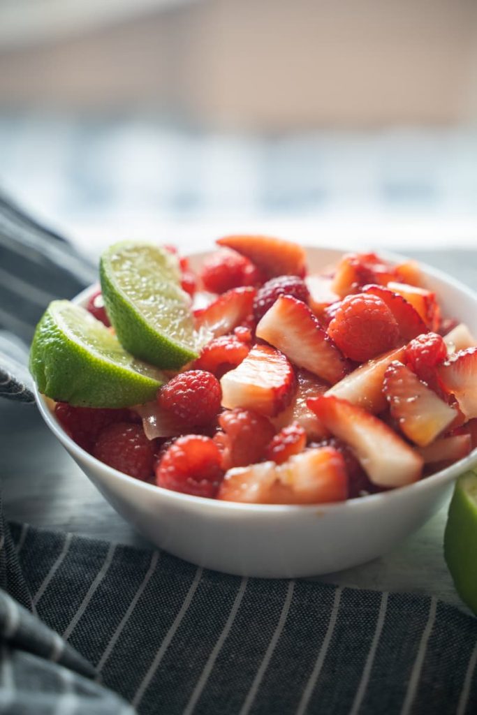 strawberry raspberry fruit salad with sliced limes on top 